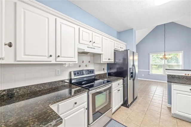 a kitchen with stainless steel appliances granite countertop a stove a sink and a refrigerator