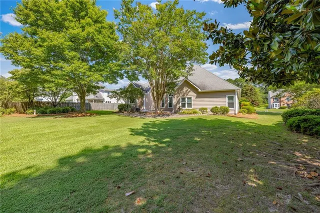 a view of house in front of a big yard with large trees