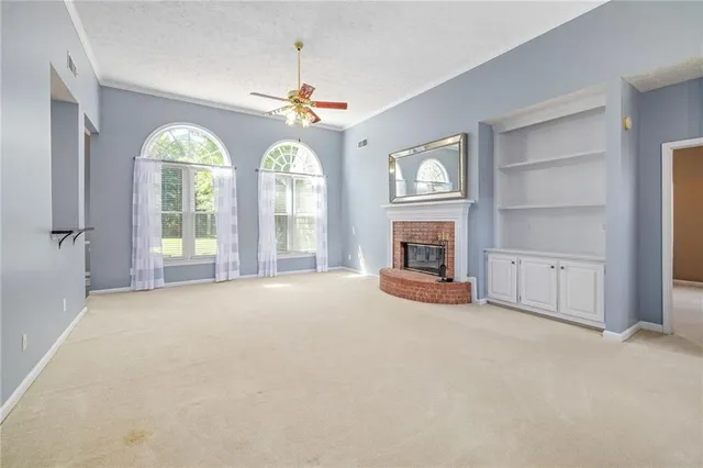 an empty room with windows fireplace and fans