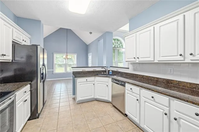 a kitchen with granite countertop white cabinets white stainless steel appliances with a sink and dishwasher