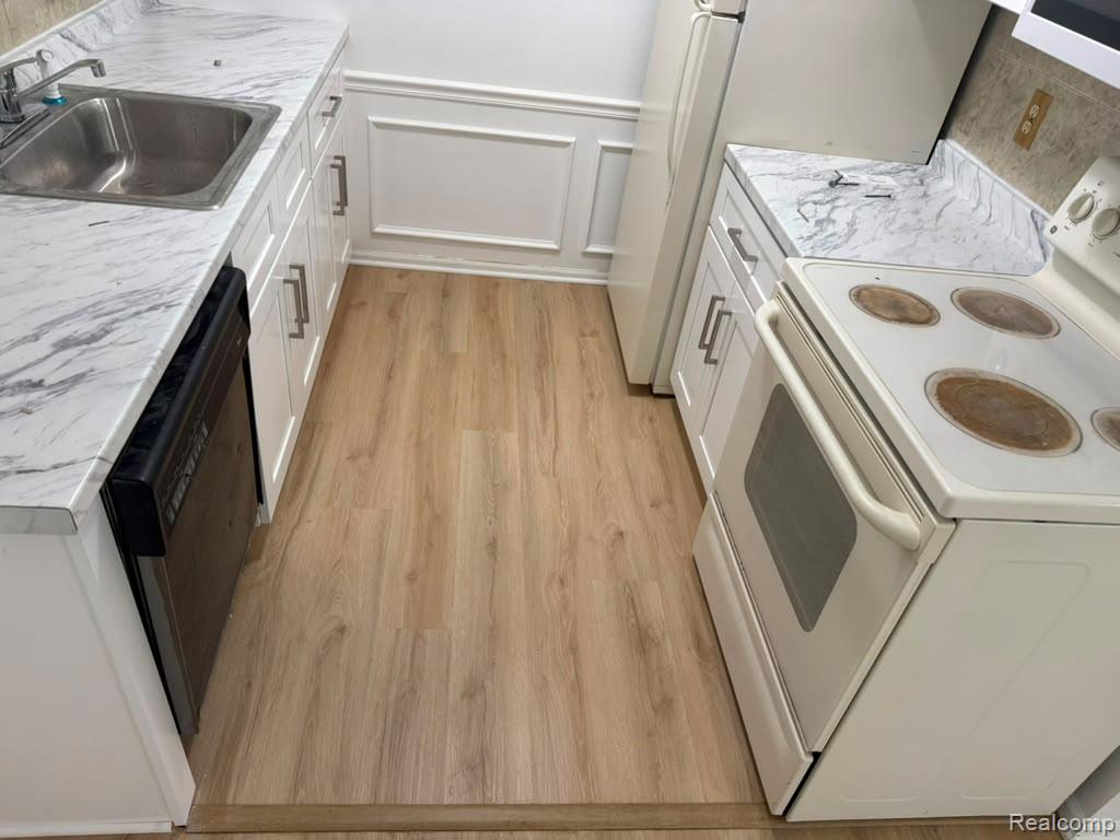 43284 Mound Road Sterling Heights, MI 48314 - Photo 19 of 19 Wood-finish flooring with white cabinetry, stainless steel sink, and a black dishwasher