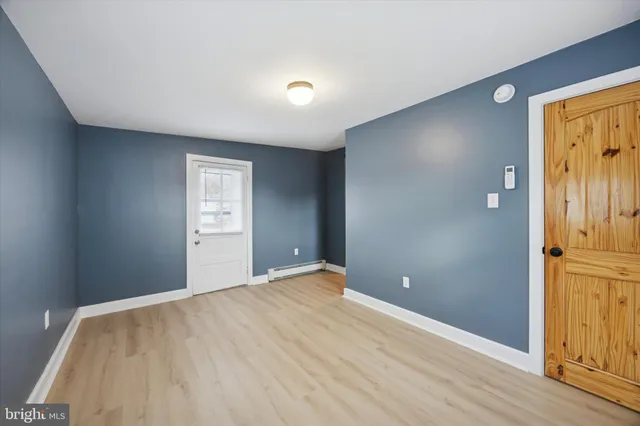 a view of an empty room with window and wooden floor