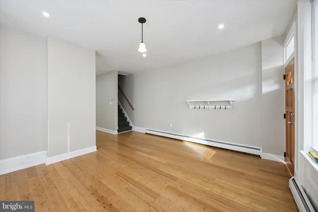 a view of an empty room with a window and wooden floor