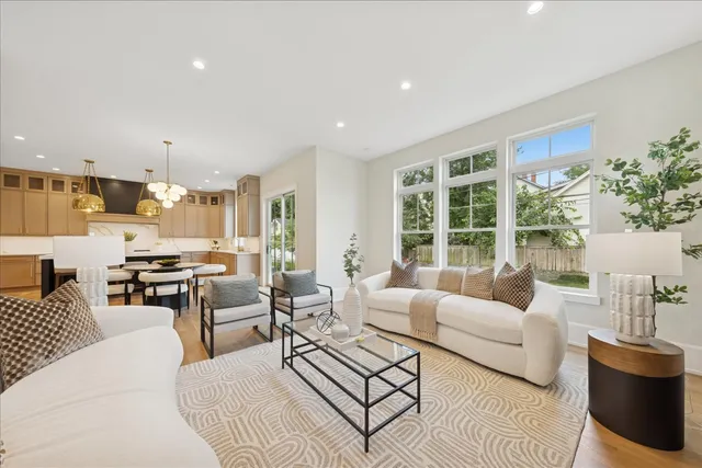 a living room with furniture large windows and kitchen view