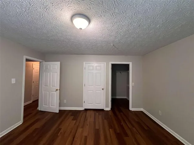 a view of an empty room with wooden floor and closet