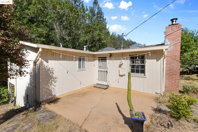 a view of a white house with a large tree and wooden fence