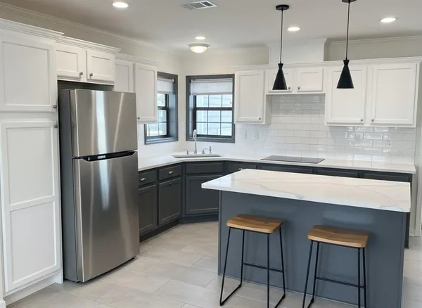 a kitchen with stainless steel appliances a refrigerator a sink a stove a kitchen island and chairs