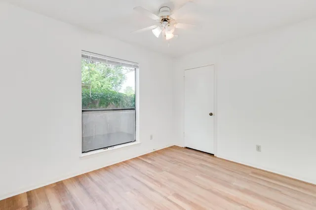 an empty room with a window and a ceiling fan