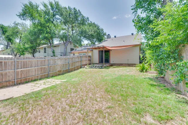 a view of a backyard with a large tree and wooden fence