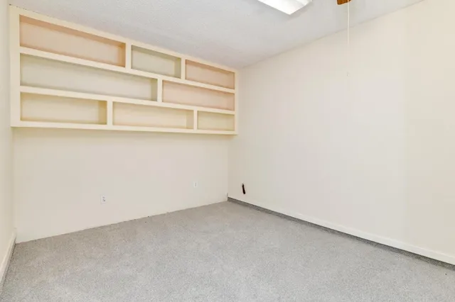 an empty room with windows and a chandelier fan