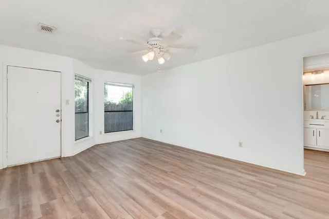 an empty room with wooden floor and windows