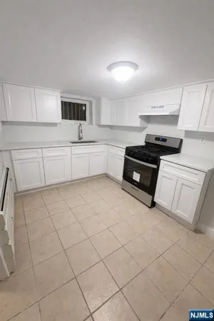 a kitchen with stainless steel appliances a stove top oven and white cabinets