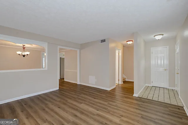 a view of an empty room with wooden floor and a bathroom