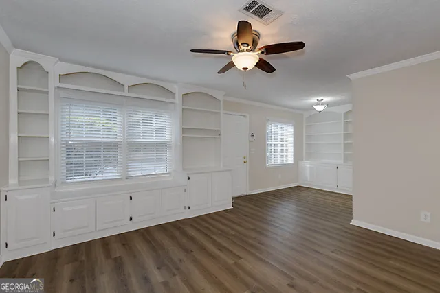 an empty room with wooden floor fan and windows