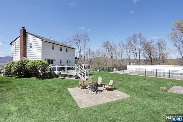 a view of a backyard with table and chairs potted plants and large tree