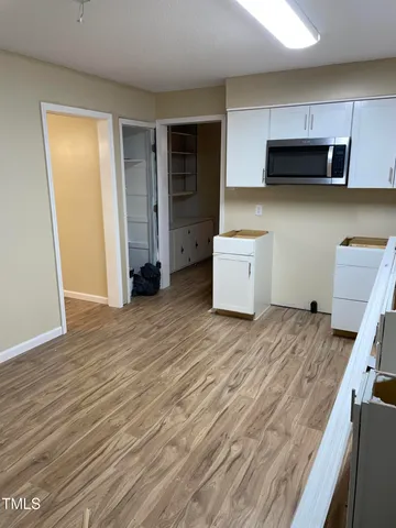 an empty room with wooden floor chandelier and windows