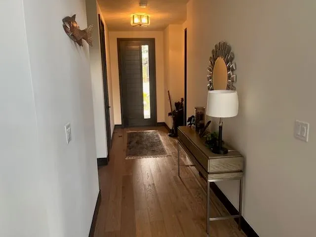 a view of a hallway with wooden floor and a bathroom