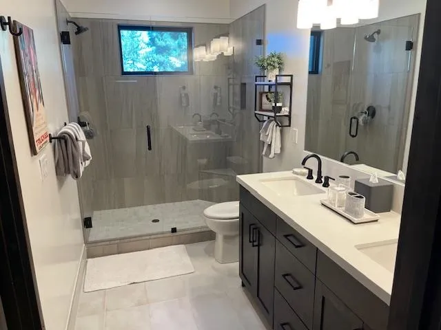 a bathroom with a double vanity sink toilet and shower