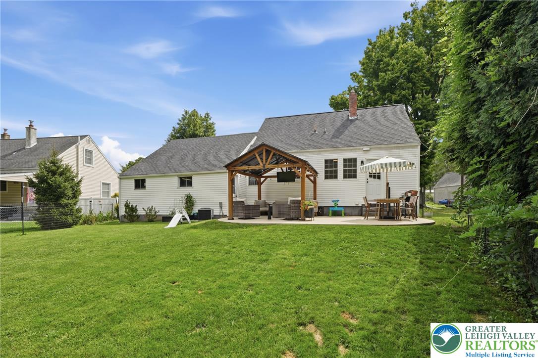 408 Maple Road Hellertown, PA 18055 - Photo 55 of 66 An expansive green lawn stretches toward a comfortable patio beneath a classic gabled roofline.