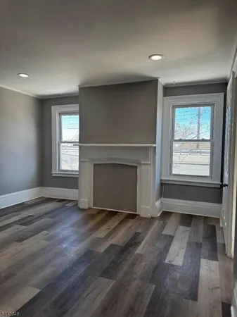 an empty room with wooden floor fireplace and windows