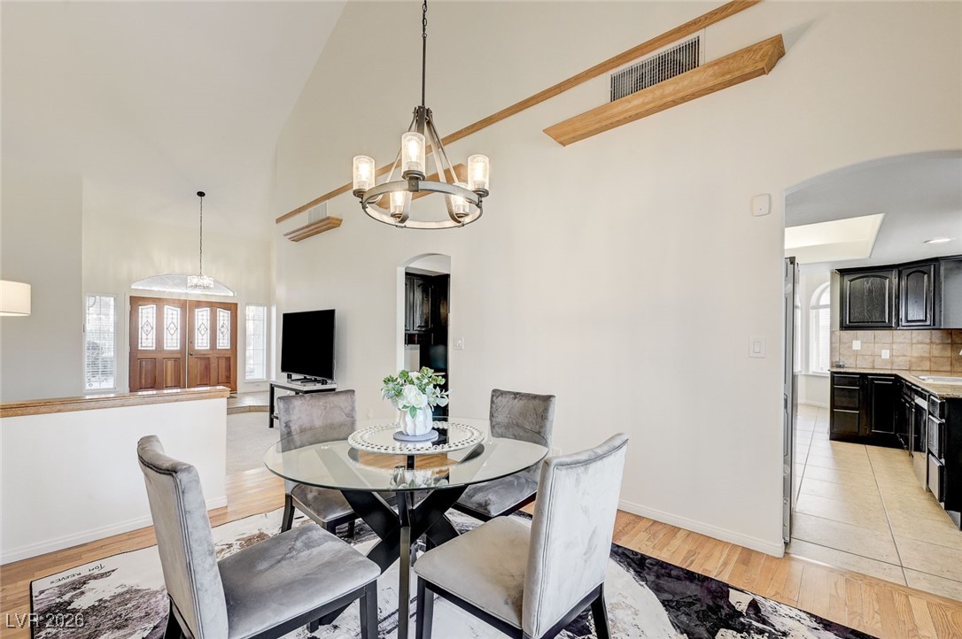 2955 El Camino Road Las Vegas, NV 89146 - Photo 3 of 99 Dining space featuring arched walkways, light wood-style floors, high vaulted ceiling, and a chandelier