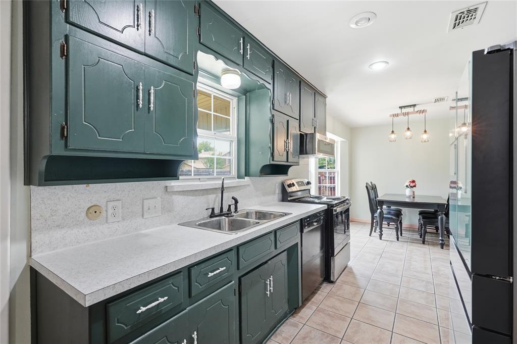 837 Springdale Road Bedford, TX 76021 - Photo 10 of 28 Kitchen featuring teal cabinetry with decorative paneling and silver-tone hardware, white speckled countertops, and a double basin sink with a black faucet