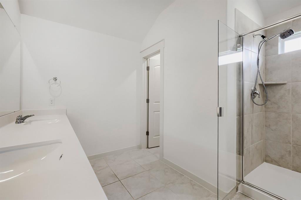 1368 Cedar Street Forney, TX 75126 - Photo 17 of 29 Dual vanity with integrated sinks, glass-enclosed shower, tiled shower surround with built-in niche, and tile flooring