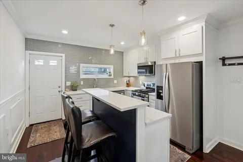 a kitchen with a refrigerator a stove a sink a dining table and chairs