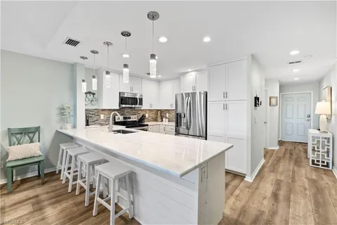 a large kitchen with kitchen island a refrigerator a stove a sink a dining table and chairs