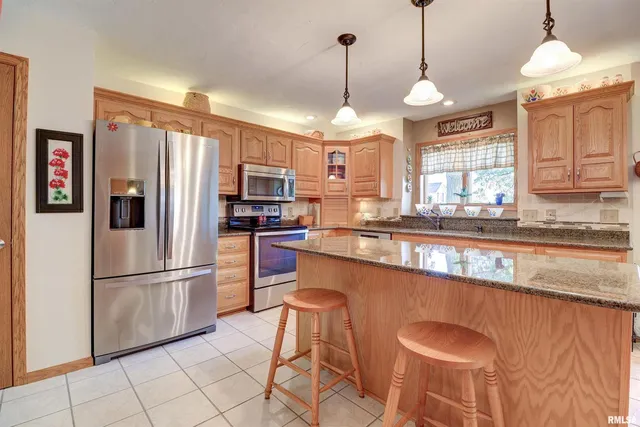 a kitchen with stainless steel appliances granite countertop a refrigerator a sink dishwasher a stove and white cabinets with wooden floor