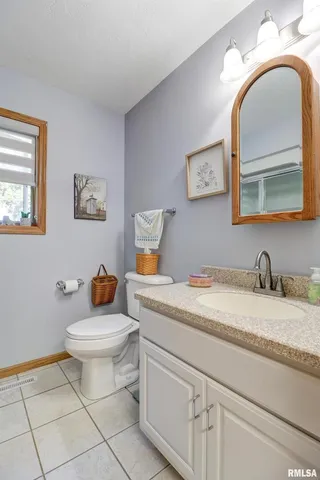a bathroom with a granite countertop sink mirror vanity and toilet