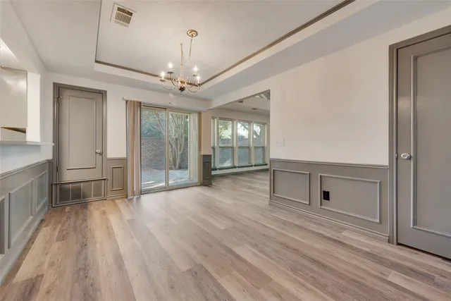 a big room with wooden floor chandelier and windows