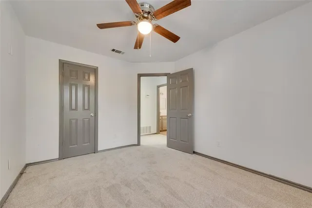 an empty room with closet and a chandelier fan