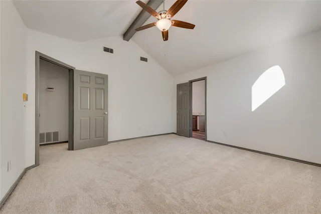 an empty room with chandelier fan and windows