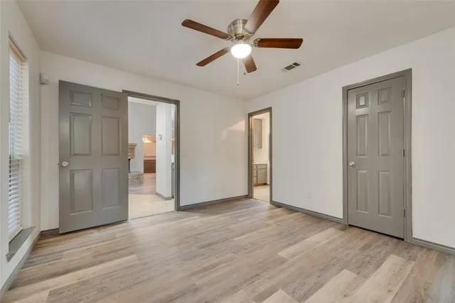 an empty room with wooden floor ceiling fan and windows
