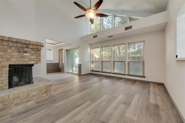 a view of an empty room with wooden floor fireplace and a window