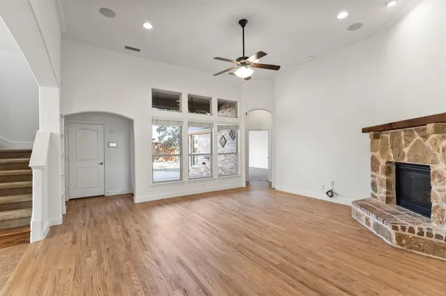 a view of an empty room with a fireplace and chandelier fan