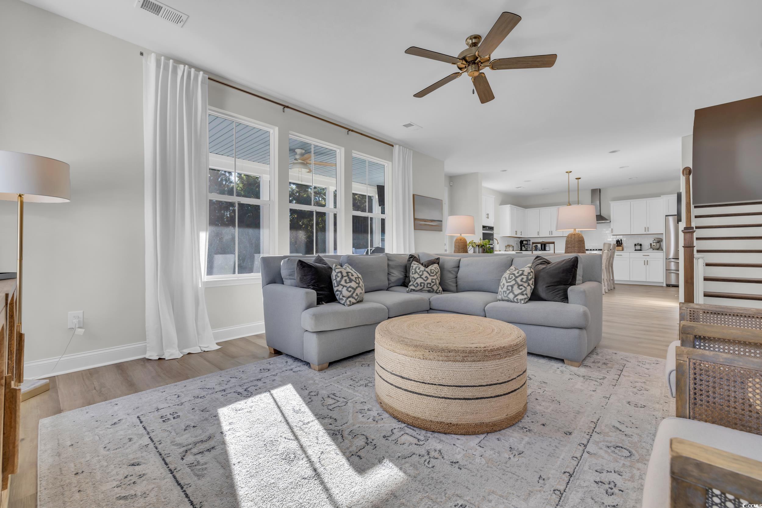 Living room with ceiling fan and light wood-type f