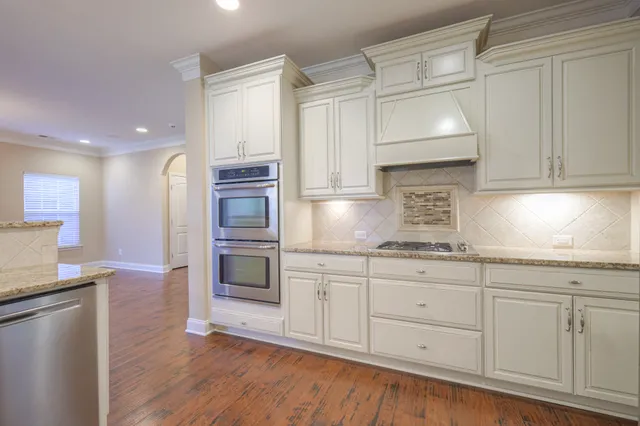 a kitchen with granite countertop white cabinets and stainless steel appliances