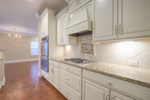 a kitchen with granite countertop white cabinets and a stove