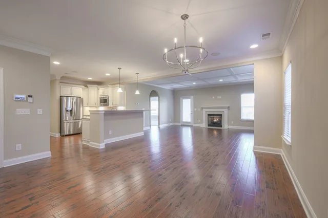 a view of a hallway with wooden floor and a kitchen