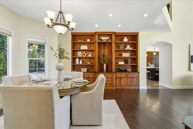 a dining room with wooden floor a chandelier a glass table and chairs