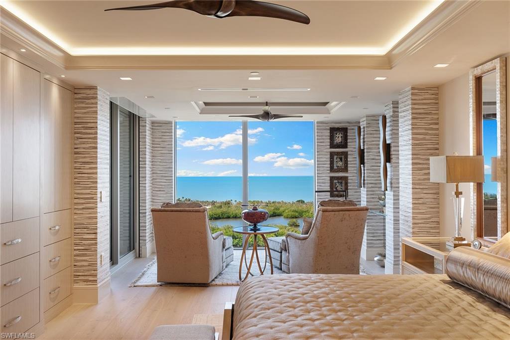 6897 Grenadier Boulevard, Unit 1202 Naples, FL 34108 - Photo 27 of 50 a bedroom with a bed and large windows