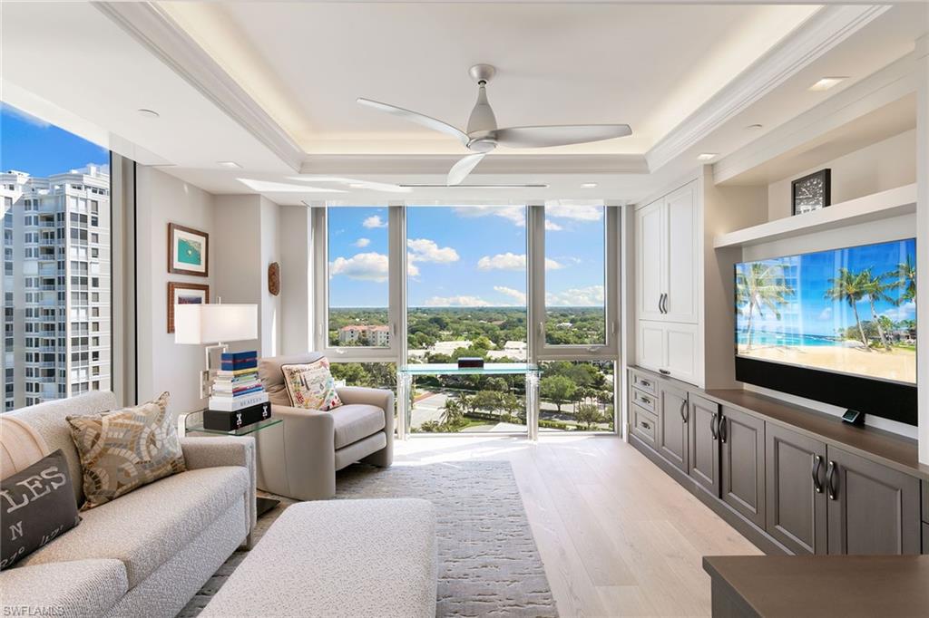 6897 Grenadier Boulevard, Unit 1202 Naples, FL 34108 - Photo 33 of 50 a living room with furniture large windows and a flat screen tv
