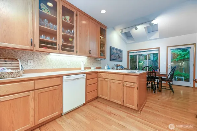 a kitchen with stainless steel appliances granite countertop wooden cabinets a dining table and chairs