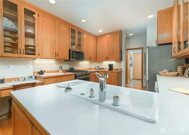 a kitchen with stainless steel appliances a stove a sink a refrigerator a center island and cabinets