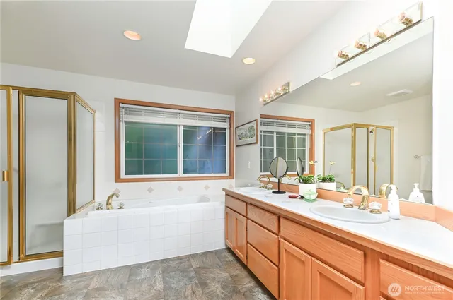 a bathroom with a sink double vanity mirror and a bathtub next to a window