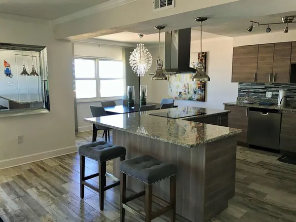a kitchen with stainless steel appliances kitchen island granite countertop a table chairs in it and wooden floors