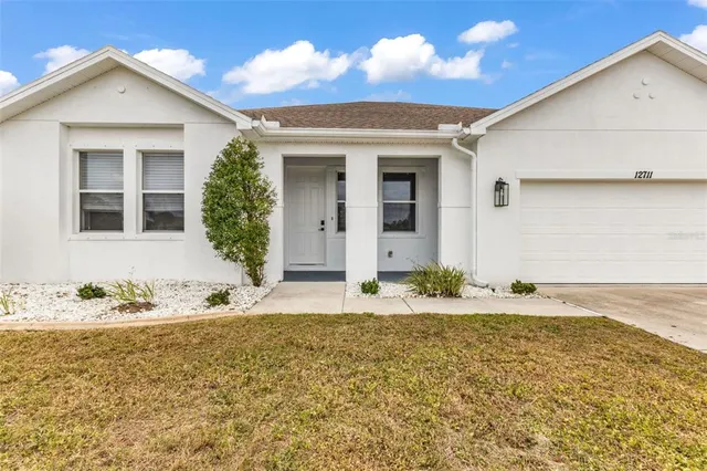 an empty room with wooden floor ceiling fan and windows