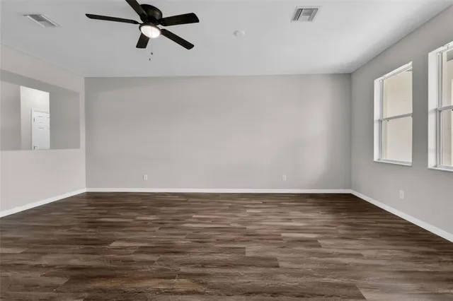 a view of empty room with wooden floor and ceiling fan